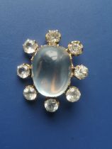 An oval moonstone cluster brooch, surrounded by seven colourless stones and one replacement paste,