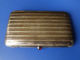 A continental silver cigarette case with inlaid gold bands, ruby coloured cabochon enamel