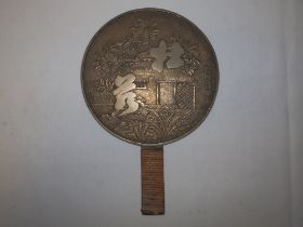 A Japanese Meiji period bronze hand mirror, cast decoration to back depicting a house with