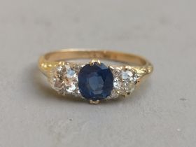 A sapphire & diamond three stone ring, the central oval claw-set sapphire flanked by two old cut