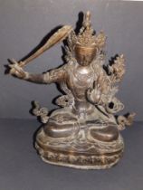 An old Eastern bronze seated deity on copper base, 11.25" high.