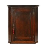 A George III oak hanging corner cupboard with barrel back,