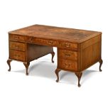 A Queen Anne style walnut pedestal desk, the top with brown gilt tooled leather,