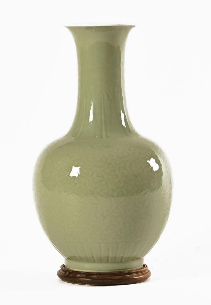 A Chinese celadon vase, with integral circular wooden stand. Height 38 cm.