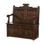 A late 19th/early 20th century carved oak box settle, with two panelled front.