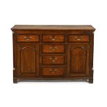 A George III oak and mahogany crossbanded dresser, fitted with a series of drawers and cupboards,