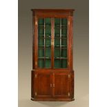 A George III oak standing corner cupboard in two sections,