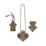 An antique Tibetan silver coloured metal lapis lazuli mounted pendant and chain, and two others.
