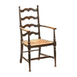 A Victorian oak country ladder back rattan seated armchair, with turned supports and shaped arms.