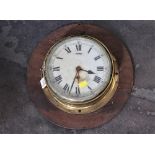 Brass bulkhead clock mounted on wooden board,