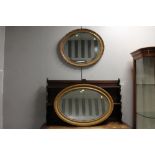 Two gilt coloured oval wall mirrors,