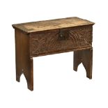 An 18th century oak small coffer, with carved front and raised on silhouette side supports.