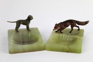 A pair of cold painted bronze ashtrays with onyx bases, in form of a fox and a Bedlington Terrier,