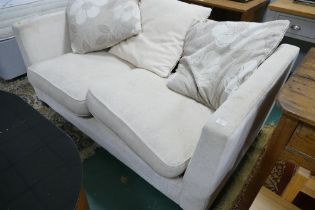 Cream upholstered two seater sofa bed / settee with floral cushions
