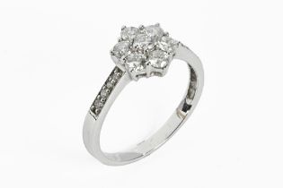 A white coloured metal diamond daisy cluster ring, with diamond set shoulders.