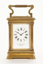 An Edwardian brass and glass panelled carriage clock, with Roman numerals and white enamel dial,