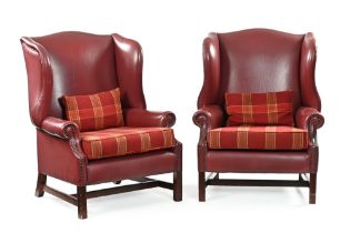 A pair of leather wing back armchairs, the seats upholstered in a red tartan material with cushions.