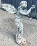 A cast metal figure of a fairy holding a bird in her hand, with verdigris style patination,