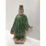 A Chinese terracotta man with green and yellow glazed robes set on a hexagaonal base in the