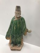 A Chinese terracotta man with green and yellow glazed robes set on a hexagaonal base in the