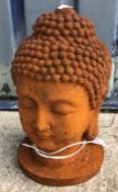 A cast metal figure of a Buddha's head, with rust style patination,