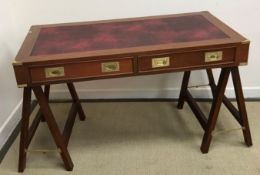 A modern mahogany framed campaign style desk with brass embellishments and handles raised on two A