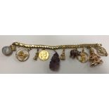 An 18 carat gold bracelet set with various charms to include a 14 carat gold Buddha,