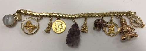 An 18 carat gold bracelet set with various charms to include a 14 carat gold Buddha,