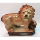 A pair of early 20th Century Staffordshire pottery figures of lions with paws on balls on a plinth