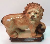 A pair of early 20th Century Staffordshire pottery figures of lions with paws on balls on a plinth