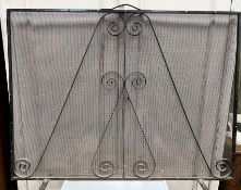 A wrought iron framed wirework spark guard 122 cm wide x 92 cm high