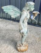 A cast metal figure of a fairy holding a shell, with verdigris style patination,