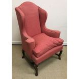 An 18th Century upholstered wingback scroll arm chair on four cabriole legs to pad feet united by
