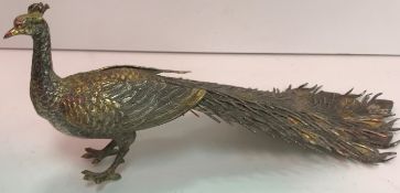 A Spanish white metal figure of a peacock with gilded decoration,