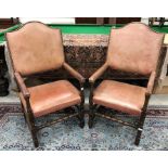 A pair of studded leather covered oak framed open arm throne type chairs in the 17th Century style