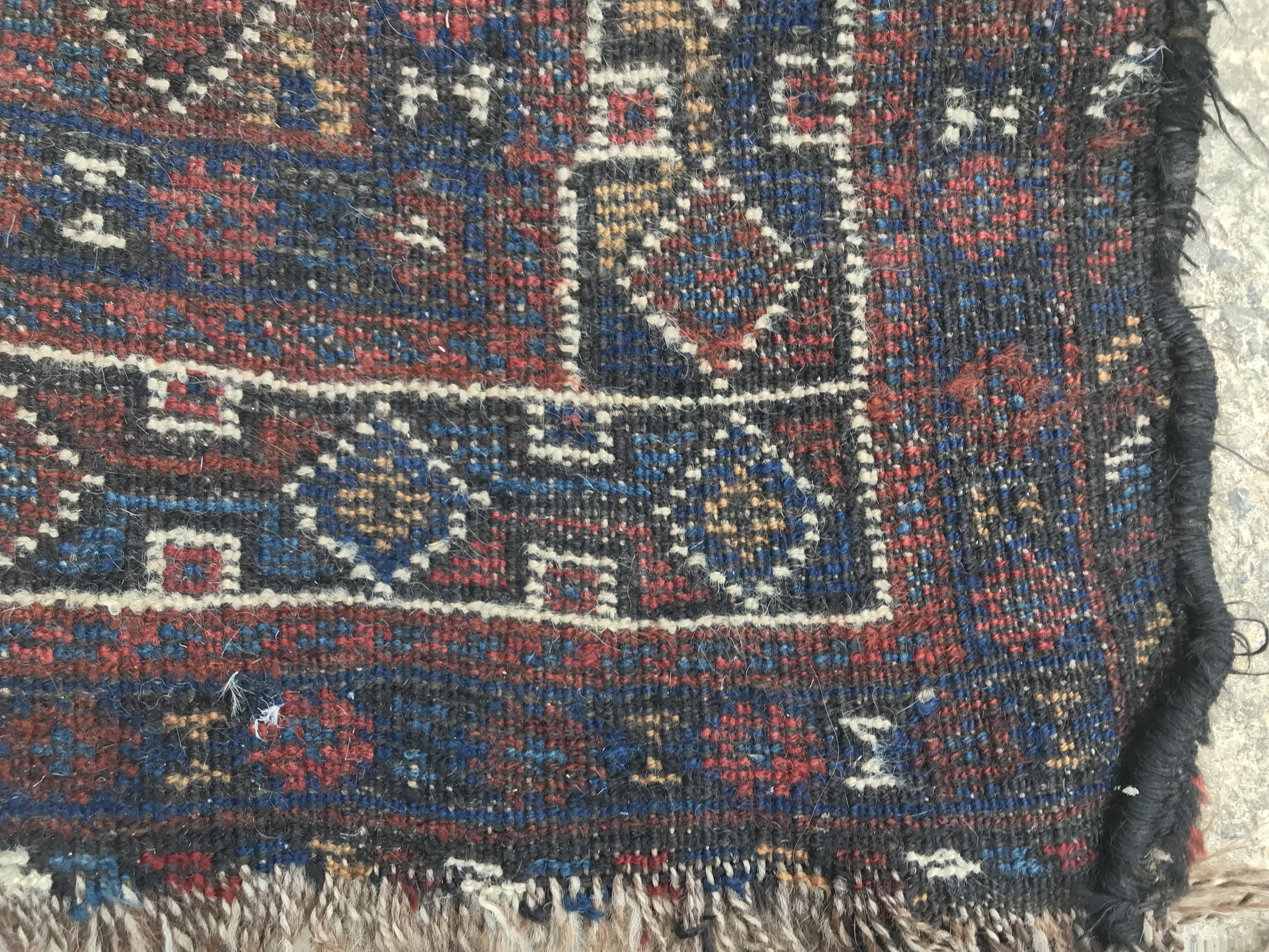 An early to mid-20th Century Persian red ground rug with repeating lozenge medallion decoration to - Image 7 of 7