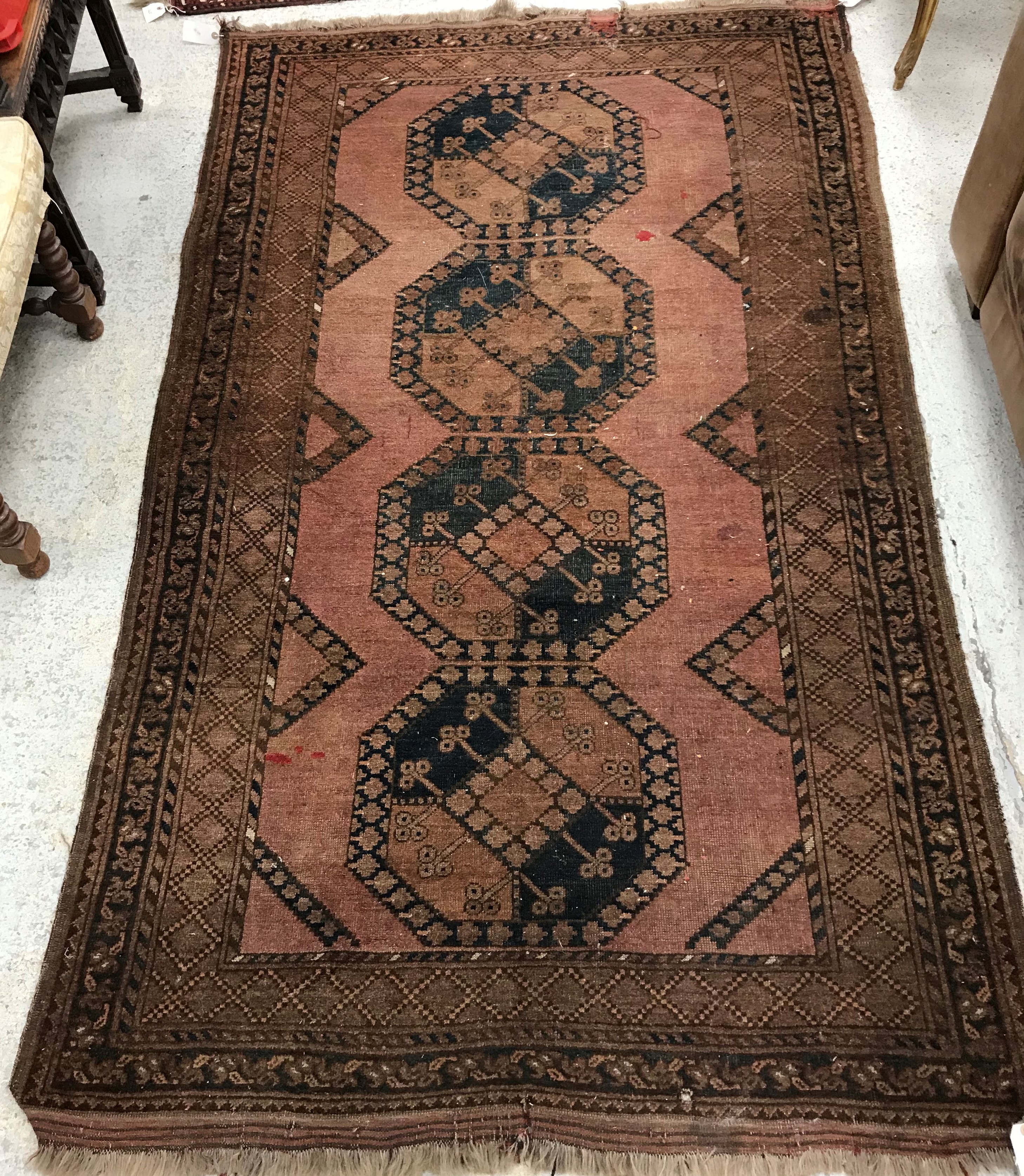 A Belouch rug, the central panel set with repeating medallions on a rust red ground,