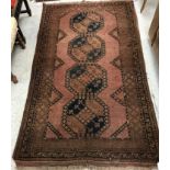 A Belouch rug, the central panel set with repeating medallions on a rust red ground,