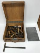 An oak case containing a selection of various engraving tools including chisels, hammers,