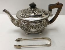 An Edwardian silver teapot with embossed scrolling decoration and ebonised handles (by Joseph