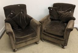 A pair of circa 1900 upholstered and studded scroll arm chairs on squat bun feet to replacement
