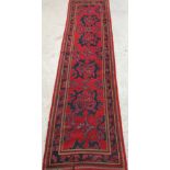 A Donegal style runner, the central panel set with repeating motifs on a red ground,