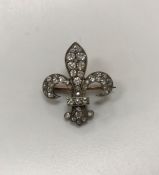 A silver and nine carat rose gold mounted old cut diamond brooch of fleur de lys form,