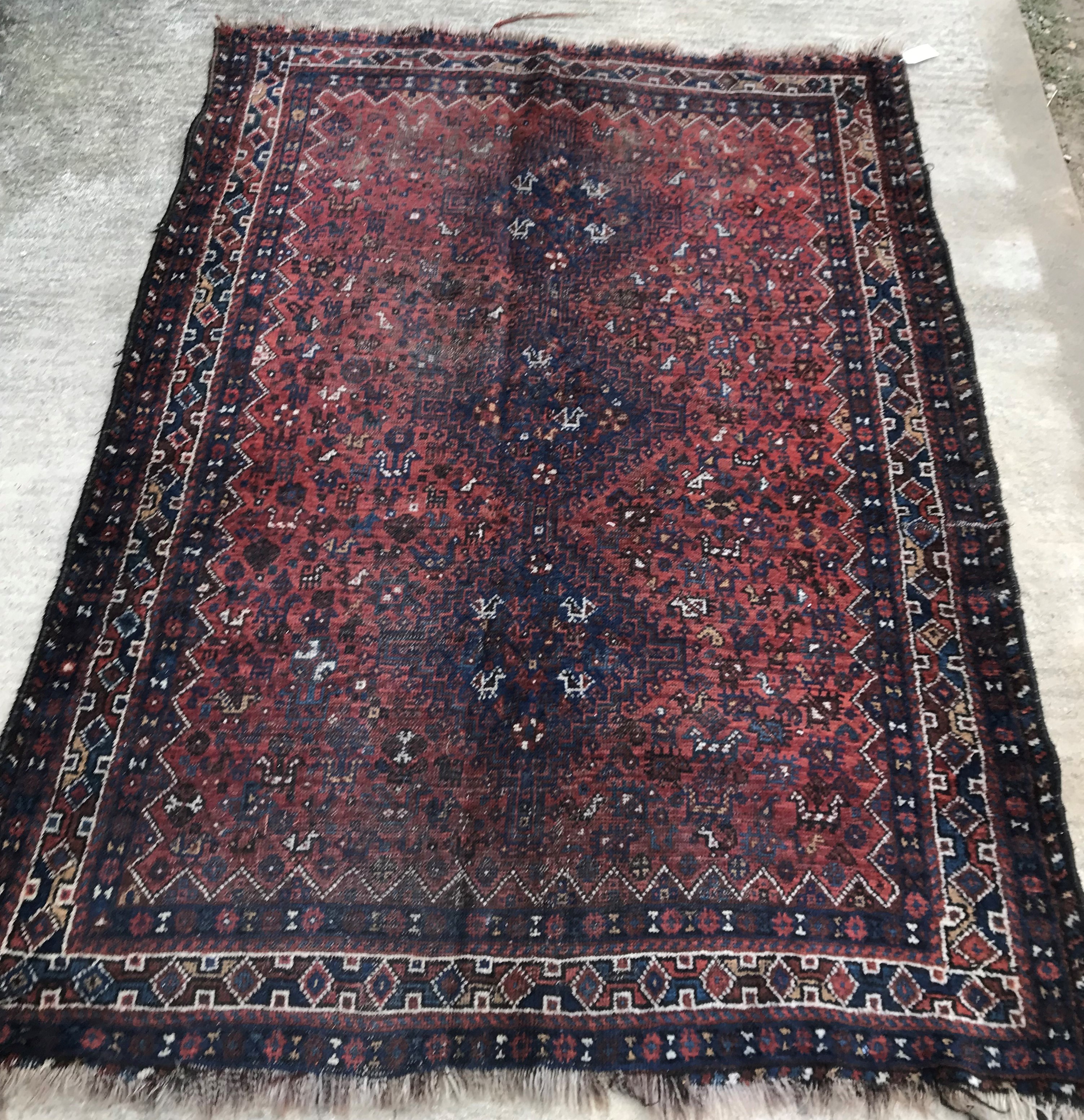 An early to mid-20th Century Persian red ground rug with repeating lozenge medallion decoration to