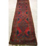 A Donegal style runner, the central panel set with repeating geometric designs on a red ground,