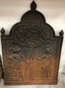 A cast iron fire back depicting gentleman in Cavalier style dress and lady beneath a fruit tree,