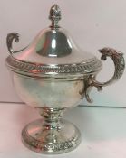 A white metal lidded cup, the lid set with acorn finial and the edge with leaf decoration,
