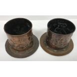 A pair of Arts & Crafts copper wine bottle coasters with embossed stylised floral decoration,