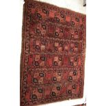 An Afghan rug, the central panel set with rows of repeating geometric design on a red ground,