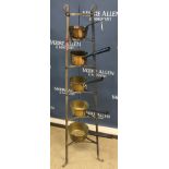 A metal six tiered saucepan stand with harlequin set of five graduated brass saucepans,